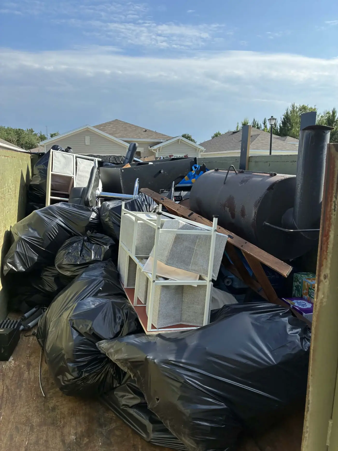 Trailer fully loaded with bagged trash, appliances, and bulky items